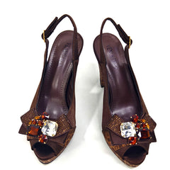 Pair of brown high-heeled shoes with decorative embellishments on a white background