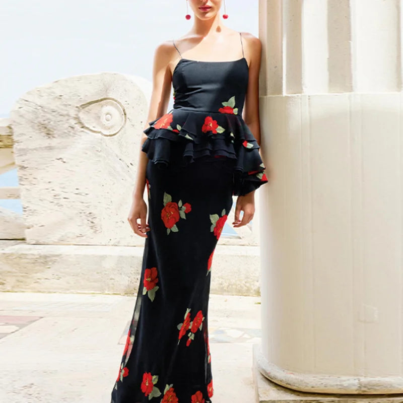Woman wearing a black floral dress standing against a white architectural background