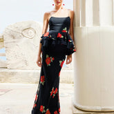 Woman wearing a black floral dress standing against a white architectural background