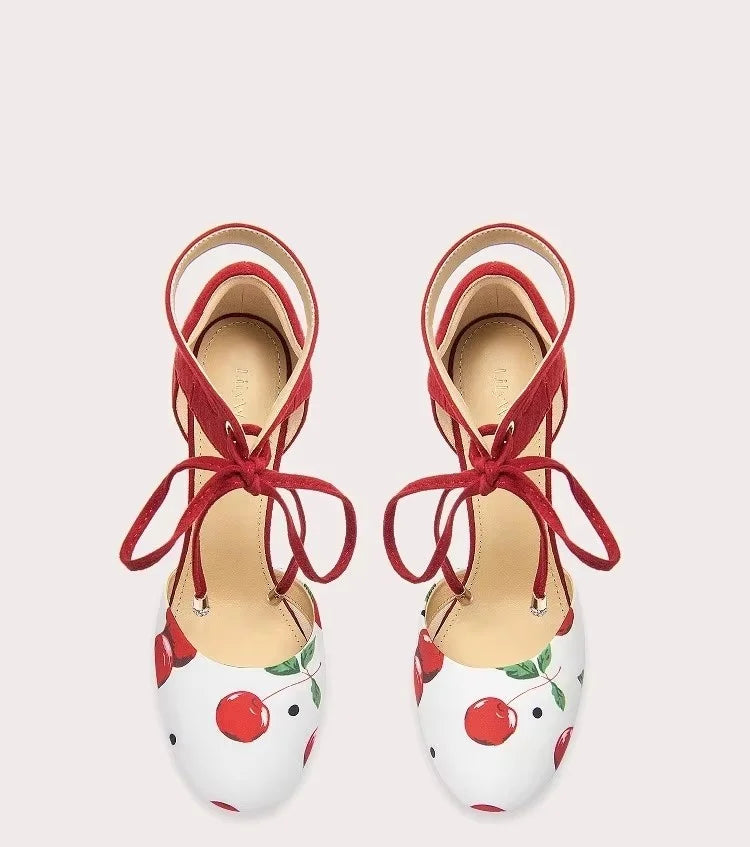 Pair of red and white shoes with cherry design on a light gray background