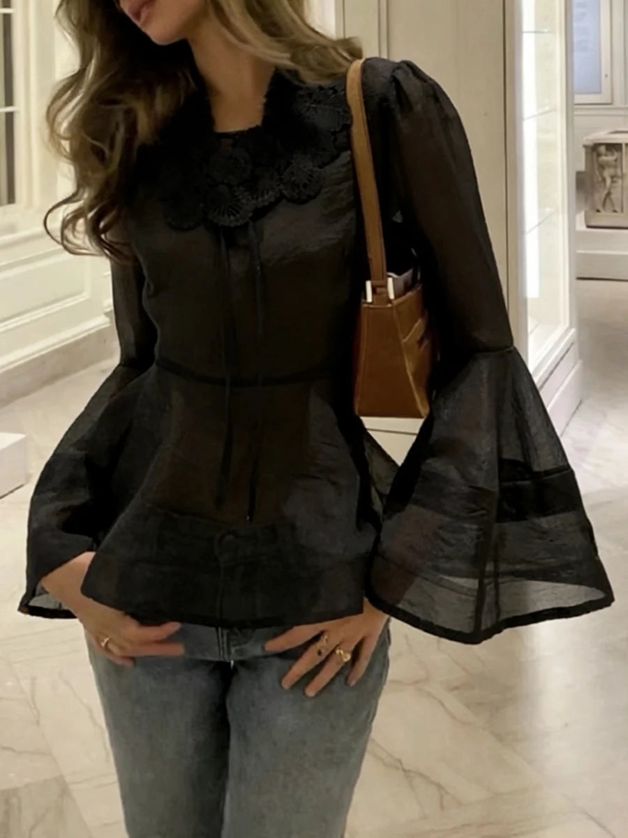 Woman wearing a black ruffled blouse and jeans in an indoor setting