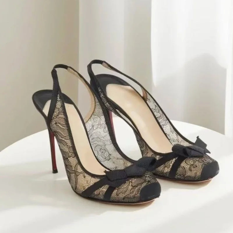 Pair of black lace slingback heels on a white surface