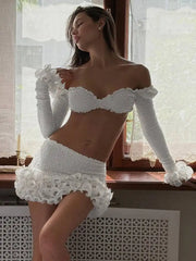 Woman wearing a white lace outfit in a softly lit room.