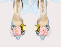 Pair of high-heeled shoes with floral decorations on a light background