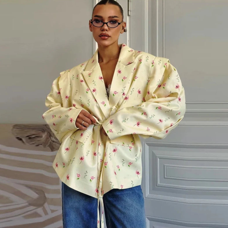 Person wearing a light yellow floral blouse with blue jeans in an indoor setting