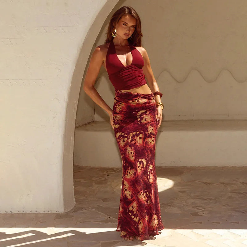 Woman in a red and patterned dress standing in a sunlit archway.