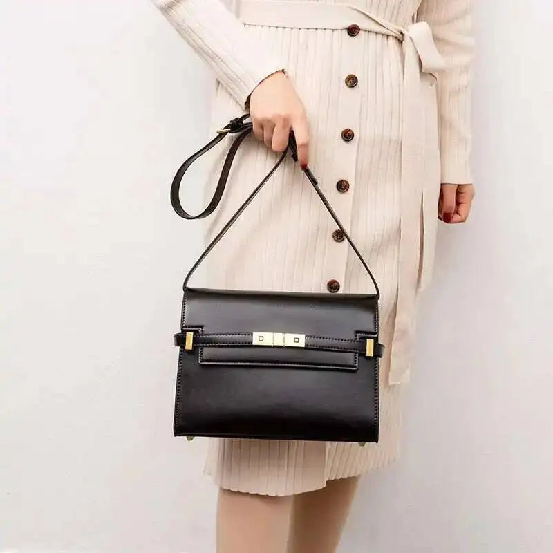 Person holding a structured black leather flap bag