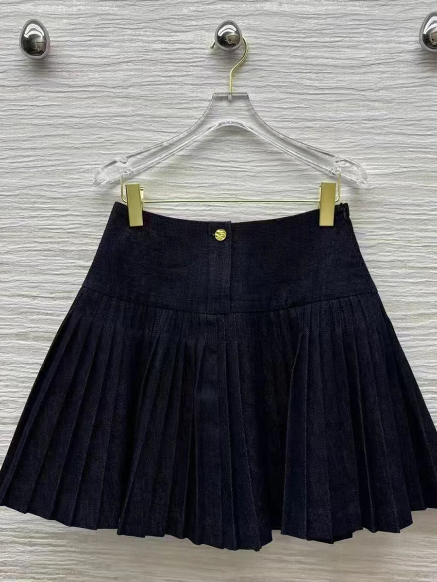 Dark Blue pleated skirt on a hanger against a textured wall.