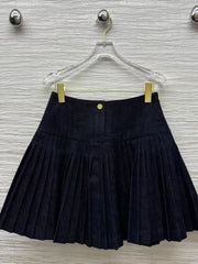 Dark Blue pleated skirt on a hanger against a textured wall.