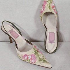 Pair of floral high-heeled shoes on a light gray background