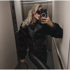 Person taking a mirror selfie wearing a black fur-lined jacket and black pants in an elevator.