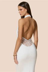 Woman wearing a white evening gown with a lace back on a beige background