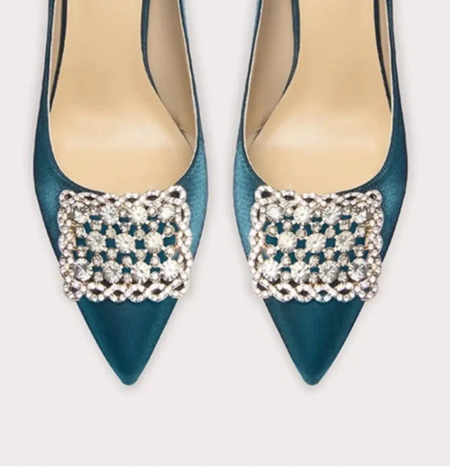 Pair of blue high-heeled shoes with decorative embellishments on a white background