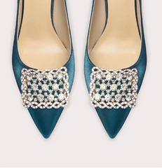 Pair of blue high-heeled shoes with decorative embellishments on a white background