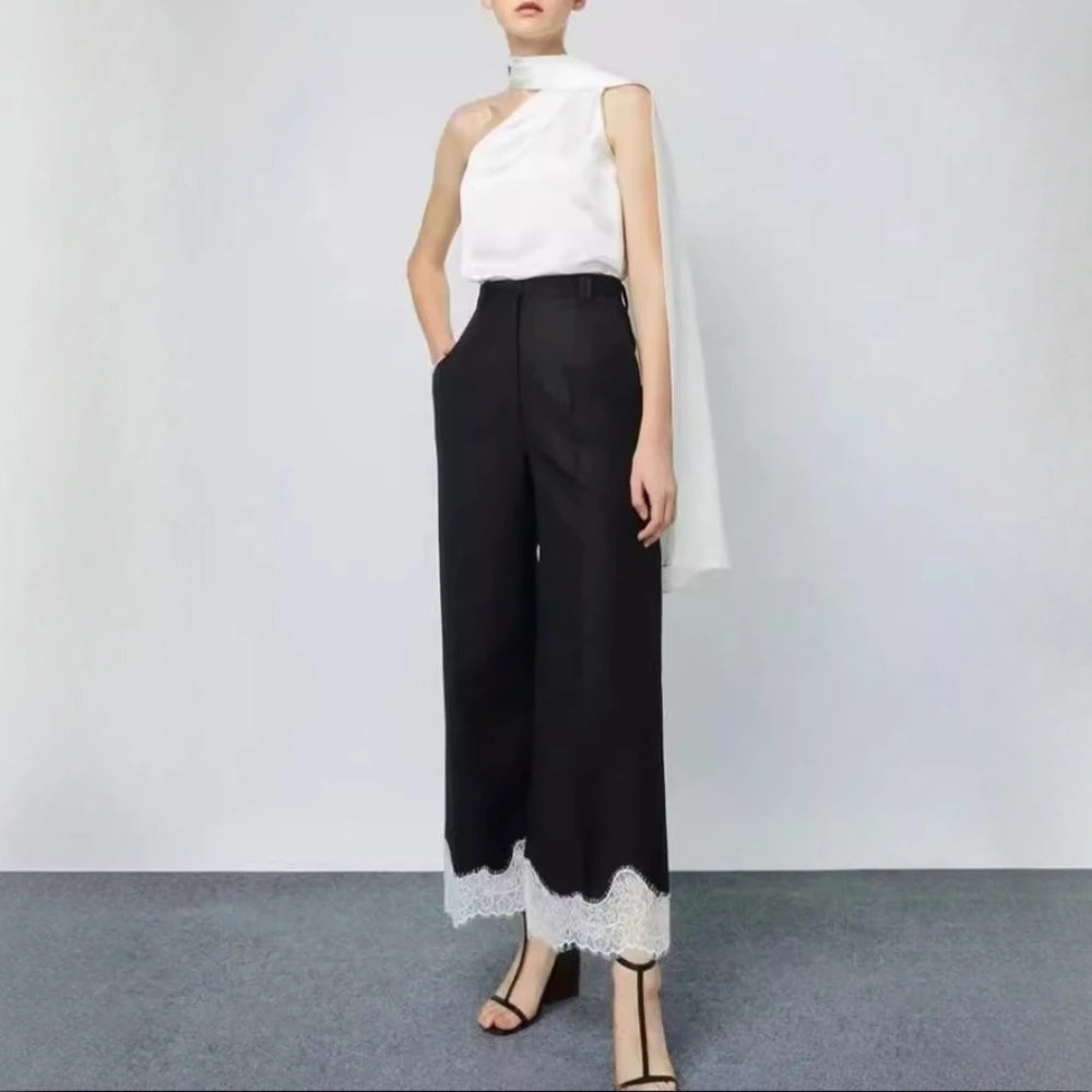 Person wearing a white sleeveless top and black pants with lace trim