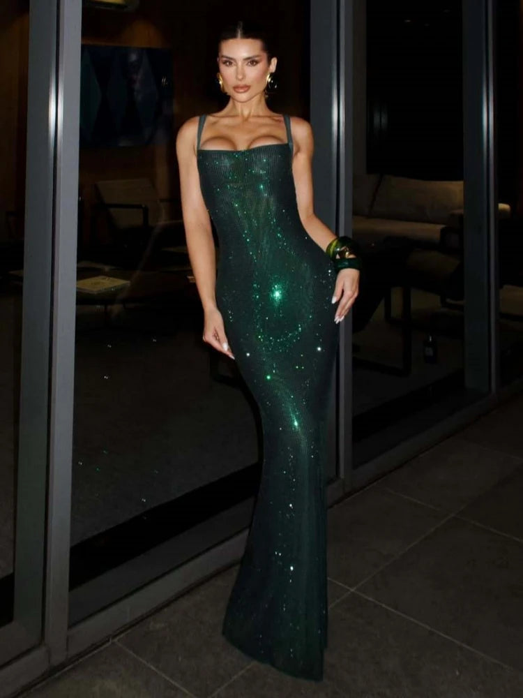 Woman in a green sequin dress standing in a dimly lit room.