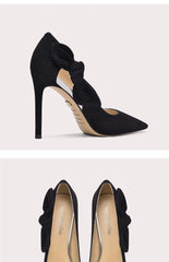 Black high-heeled shoes with bow detail on a light gray background