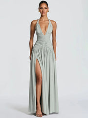 Woman wearing a light green halter neck gown with a slit on a white background