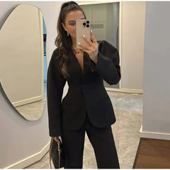 Person wearing a black suit taking a mirror selfie.