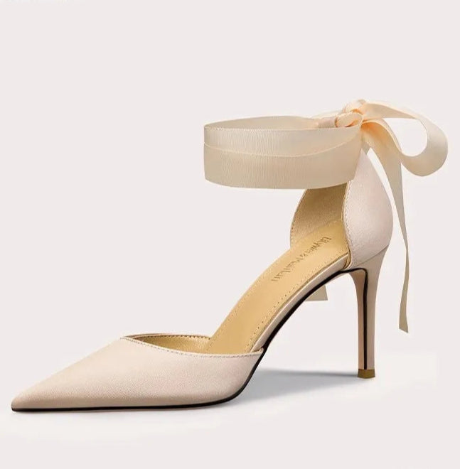 Beige high-heeled shoe with ankle strap on a light gray background