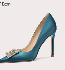 Blue high-heeled shoe with a decorative brooch on a white background