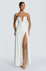 Woman wearing a white strapless gown with a high slit on a white background