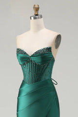Green strapless evening gown with beaded details on a mannequin against a gray background