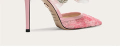 Pink high-heeled shoes with floral design on a white background