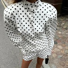 White blouse with black polka dots worn by a person on a street.