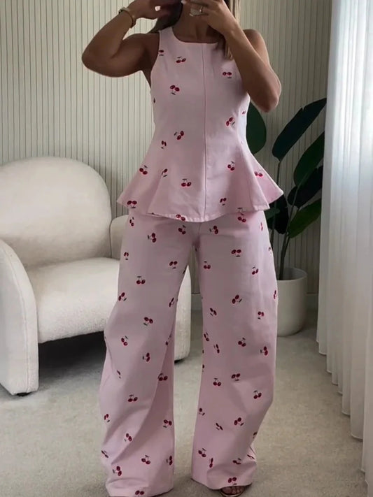 Pink cherry print peplum top and wide leg pants set on a woman indoors.