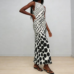 Woman wearing a black and white polka dot dress against a plain background