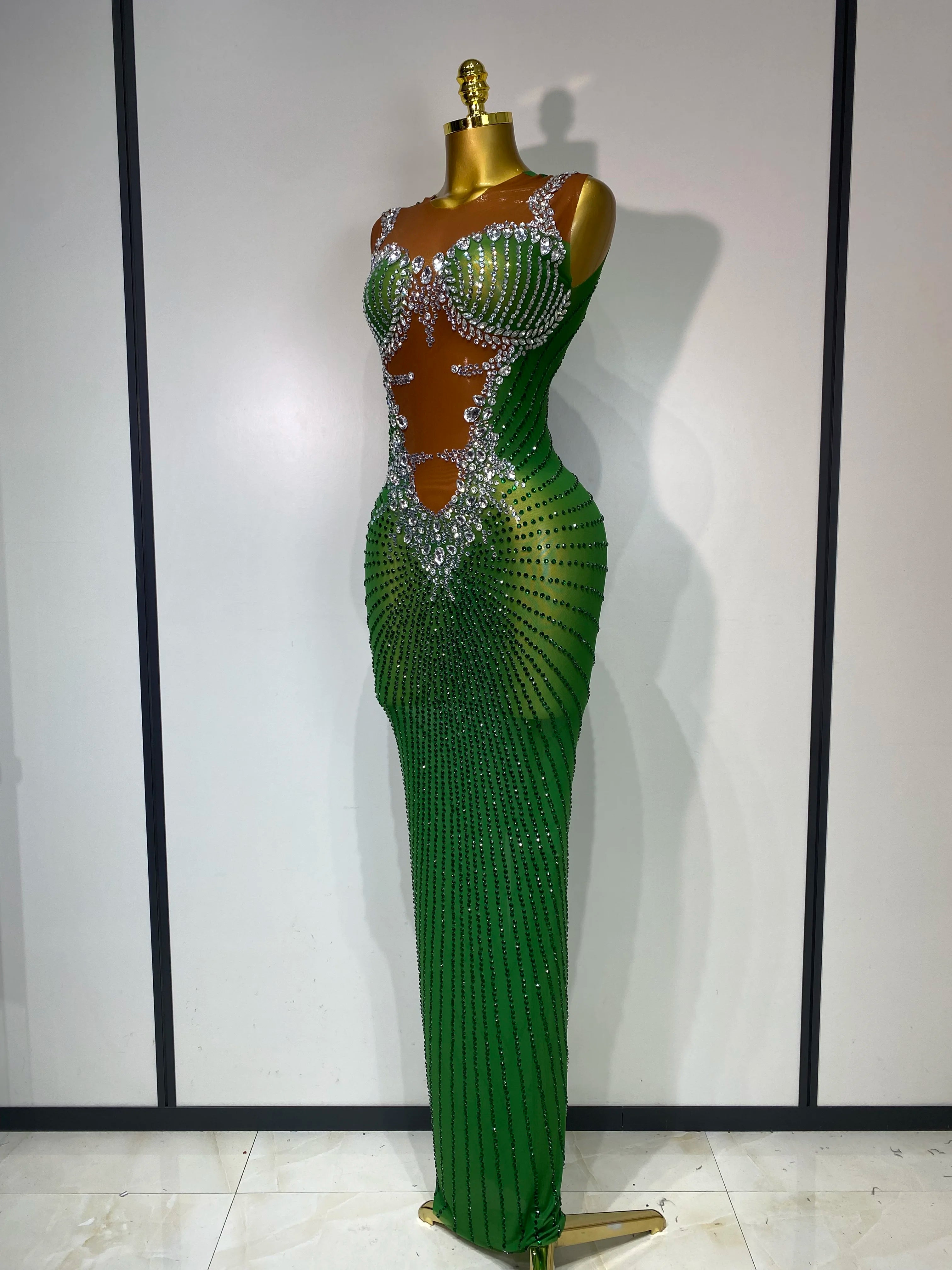 Green evening gown with beaded details on a mannequin against a white wall.