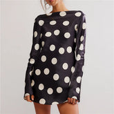 Black dress with white polka dots on a plain background