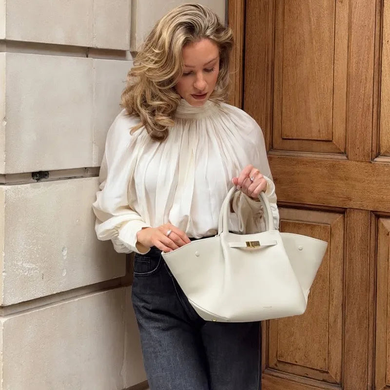 Woman holding a white handbag against a wooden door.
