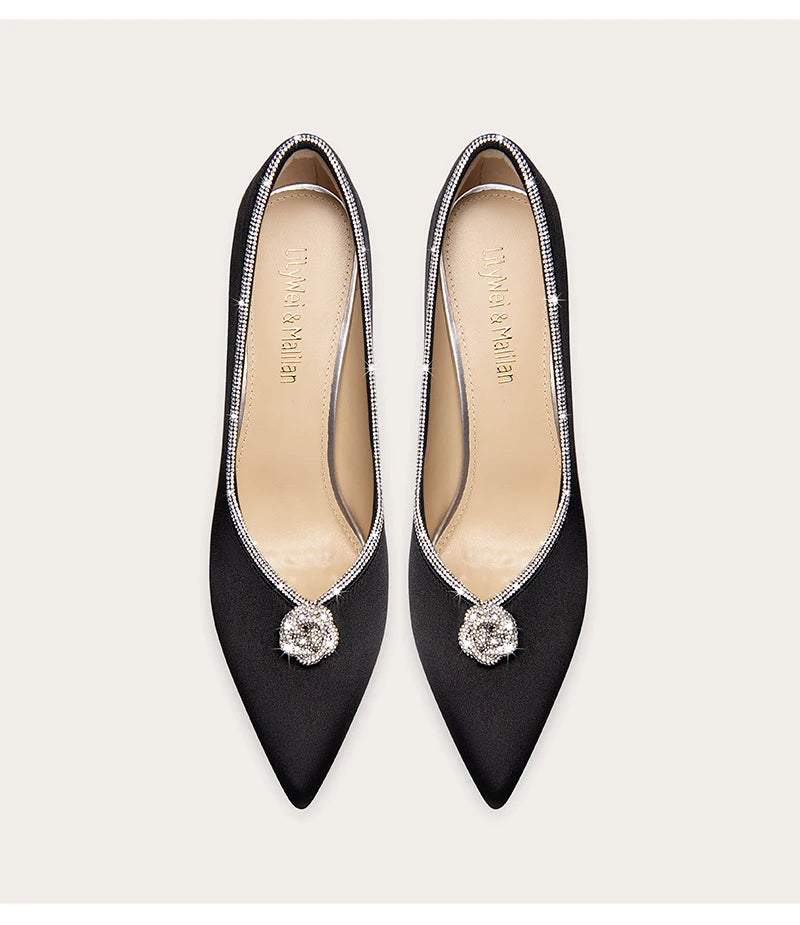 Pair of black pointed-toe shoes with decorative elements on a white background