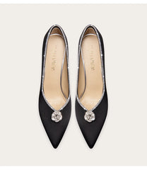Pair of black pointed-toe shoes with decorative elements on a white background