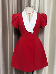 Red dress with white collar on a mannequin against a beige curtain background