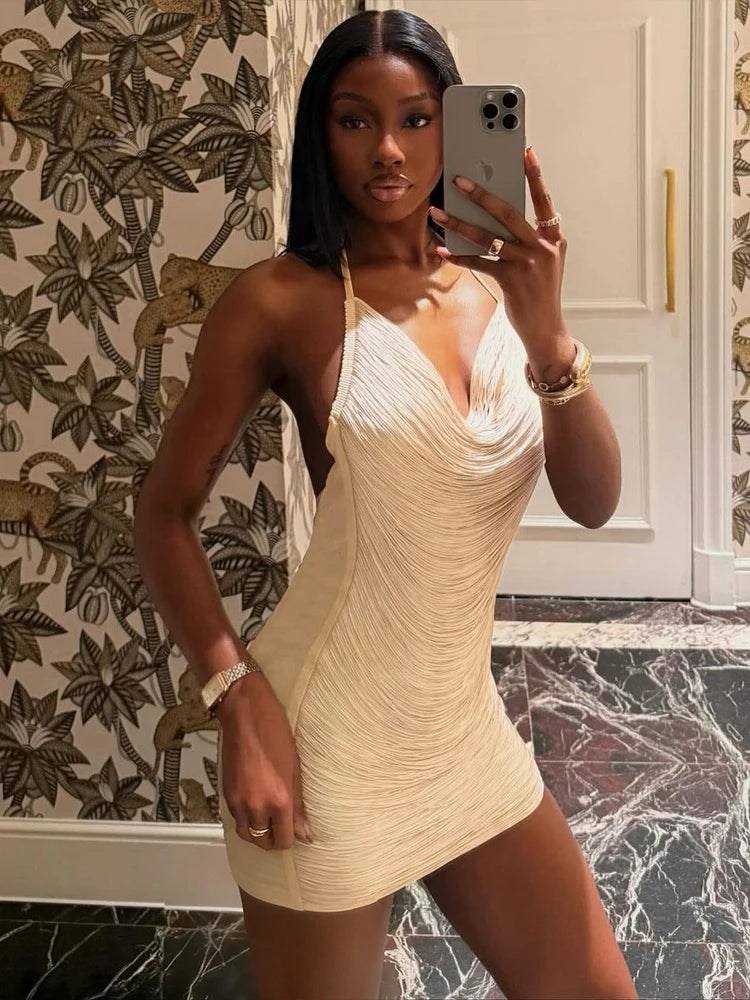 Woman taking a mirror selfie wearing a beige dress in a room with decorative wallpaper.