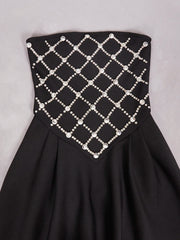 Black strapless dress with a grid pattern of pearls on a gray background