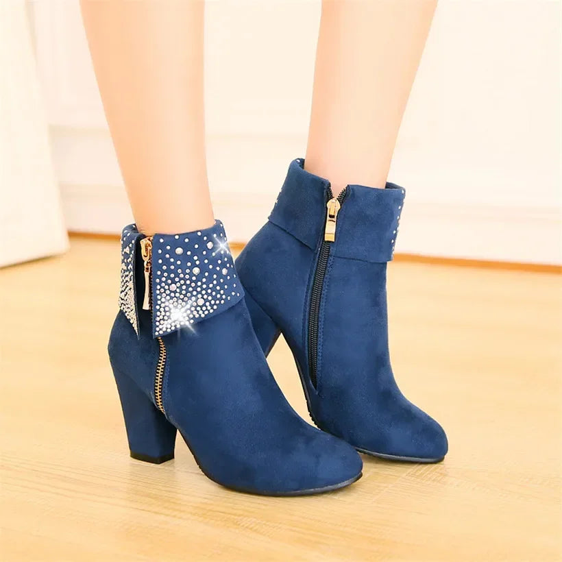 Blue ankle boots with decorative elements on a light wooden floor.