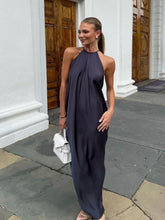 Woman in a dark blue halter neck dress standing outside a building with wooden doors.