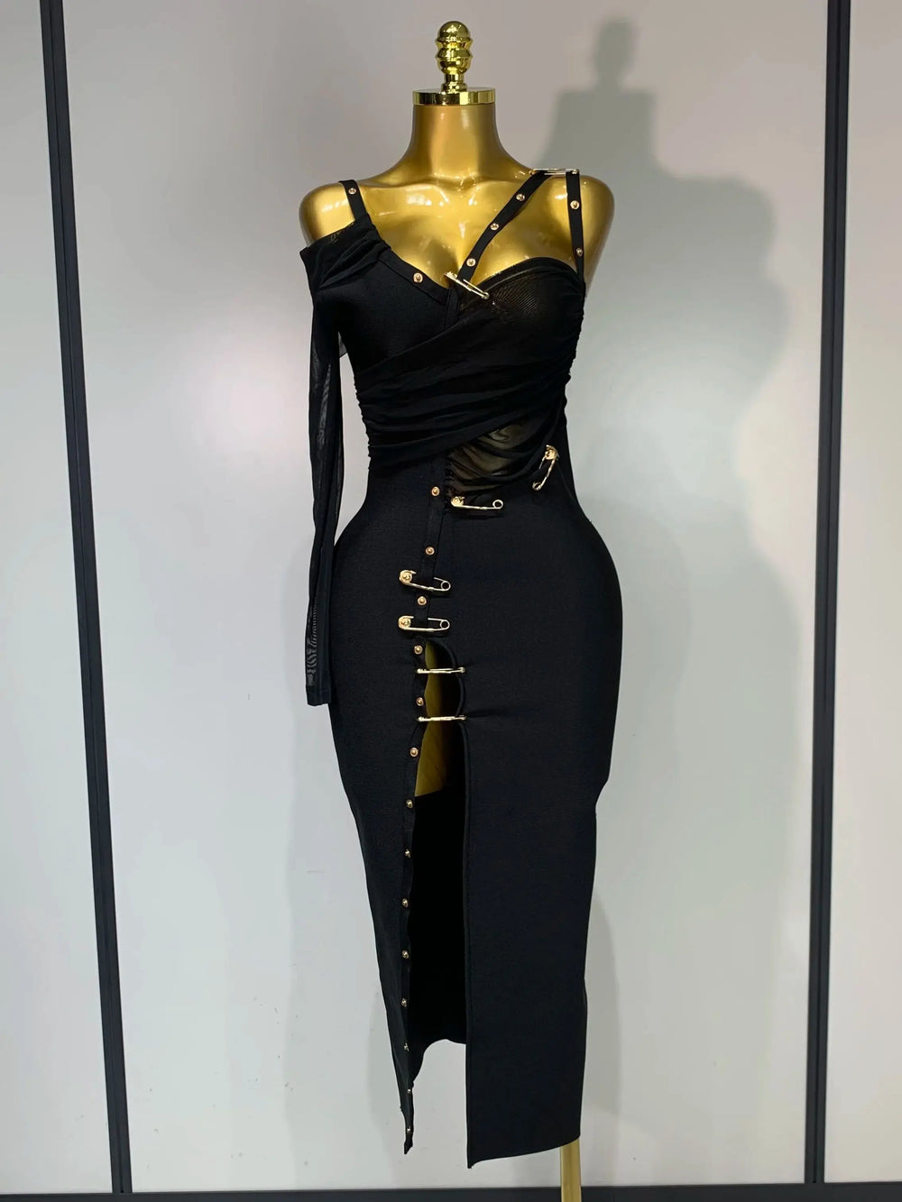 Black dress with gold accents on a mannequin against a plain background