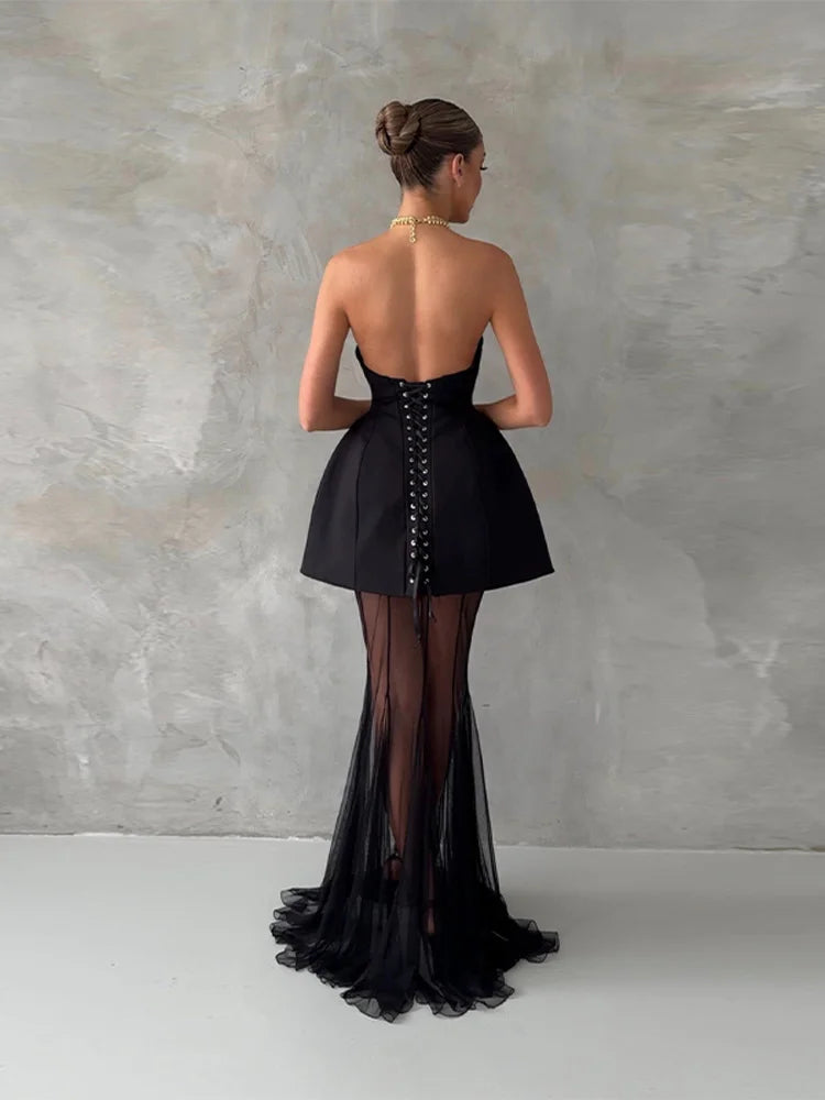Black evening gown with sheer panels on a plain background
