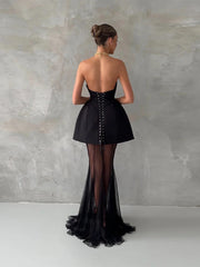 Black evening gown with sheer panels on a plain background