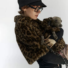 Person wearing a leopard print coat holding a small dog on a white background