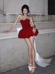 Woman in a red dress sitting on a stone ledge.
