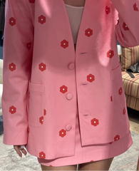 Pink blazer with red floral patterns worn by a person