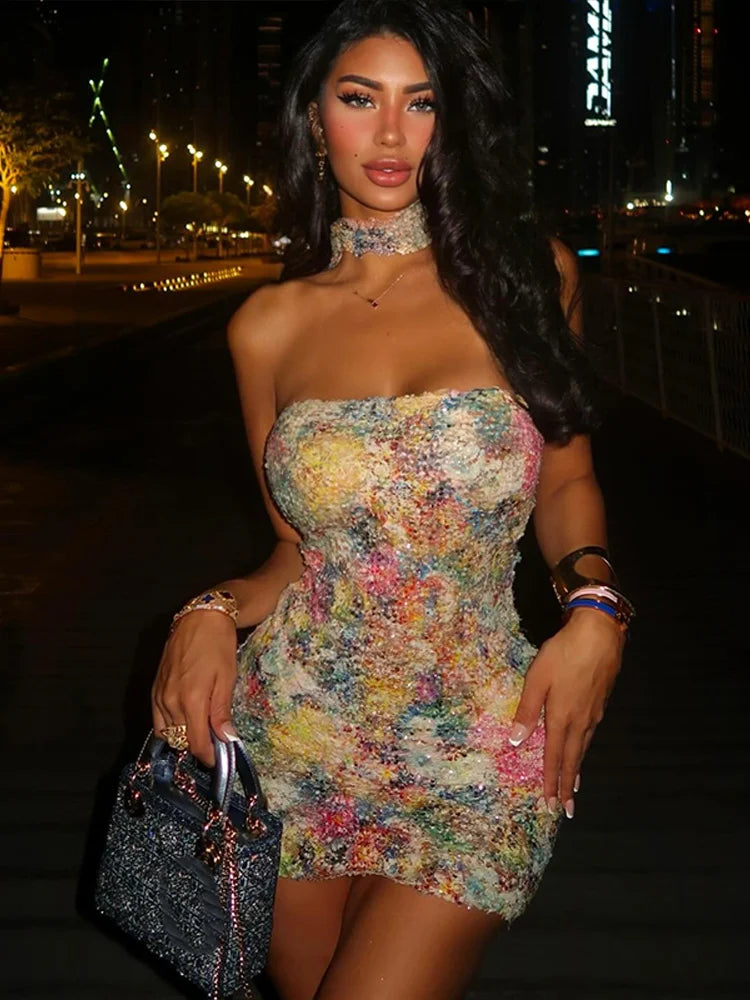 Woman in a colorful dress holding a handbag at night.