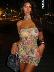 Woman in a colorful dress holding a handbag at night.