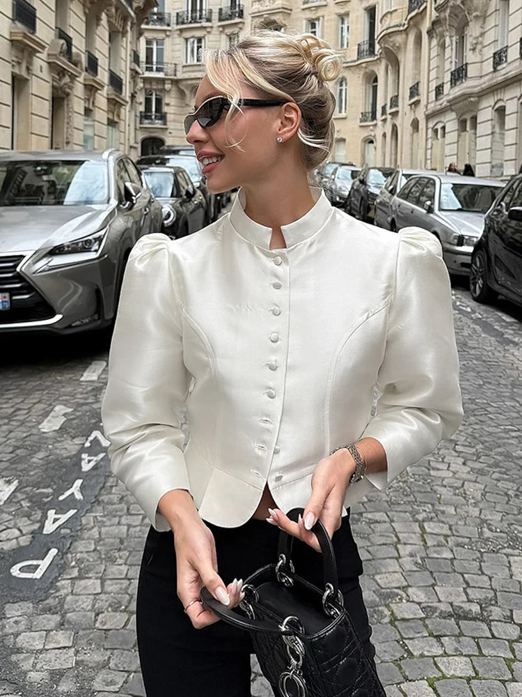Woman in a white blouse with puffed sleeves on a city street.